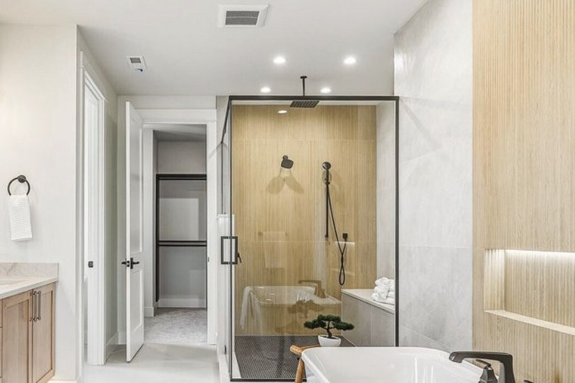 After: bathroom with a wood-look tile shower, glass enclosure and closet doorway