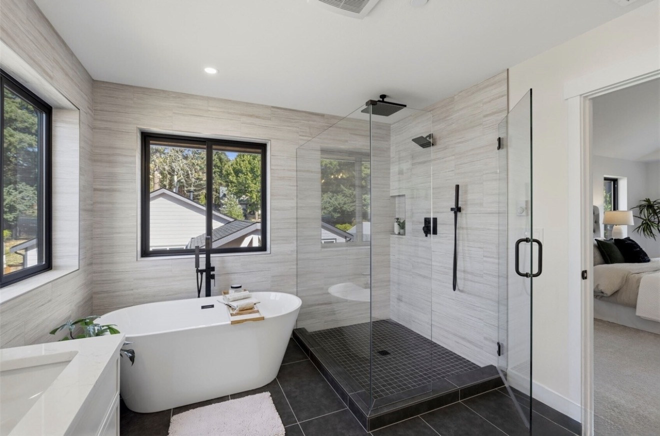 Frameless glass shower with linear tile walls and black mosaic shower floor