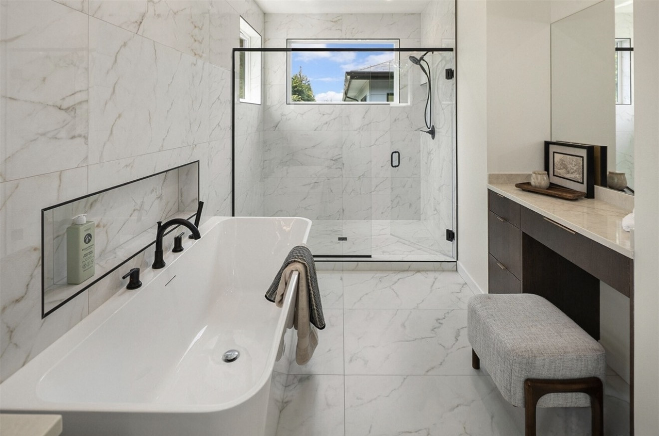 Marble-look bathroom with a long tub niche, freestanding tub and walk-in shower